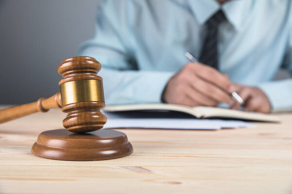 Молот и судья пишет на бумаге на сером фоне