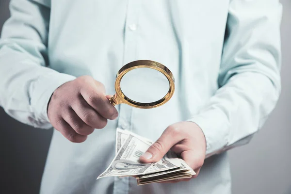 young man checks money with a magnifying glass