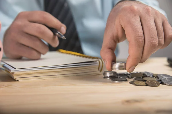 Bir adam hesaplamalar yapar ve bir deftere yazar.