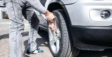 Bir adam arabanın çarkını değiştirir.