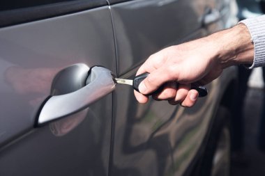 Bir anahtarla arabanın kapısını açar.