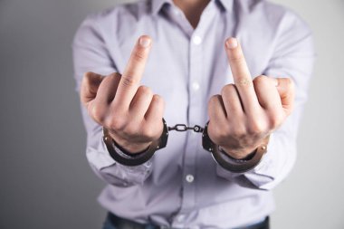 Orta parmağını gösteren kelepçeli bir adam.