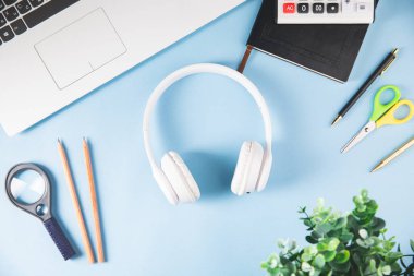 masaüstü, kulaklıklar, büyüteç, hesap makinesi, dizüstü bilgisayar ve kalemler masaya.