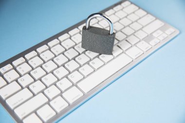 Beyaz arkaplandaki klavyede metal kilit