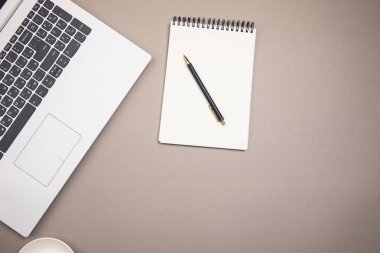 dizüstü bilgisayar, not defteri ve kalem masaya.