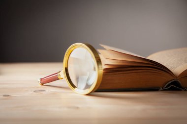 Büyüteç ve kitap ahşap masada.