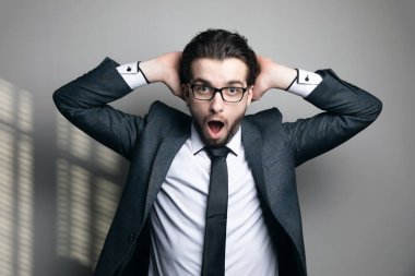 Konsept insanı şaşırttı. Takım elbiseli ve gözlüklü bir adam ellerini başının arkasına koyup gri bir arka planda ağzını açtı.