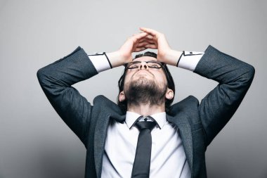 Takım elbiseli ve gözlüklü bir adam tepede yorgun görünüyor.