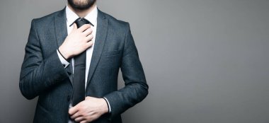 Takım elbiseli ve gözlüklü bir adam kravatını düzeltir.