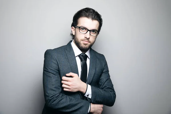 a man in a suit and glasses stands on a gray background