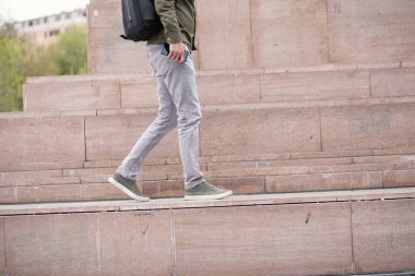 Genç bir adam sokakta çantasıyla yürüyor.