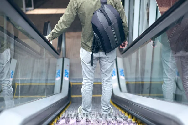 Metronun çelik yürüyen merdiveninde yürüyen bir adam.