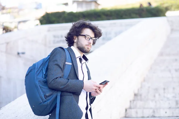 in a suit walks on the street with a bag holding a phone