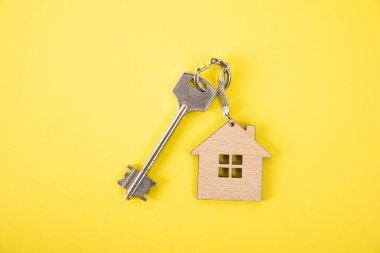 Turuncu arka planda anahtarlığı olan ev anahtarları.