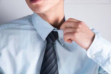Gömlekli bir adam yakasını düzeltir.
