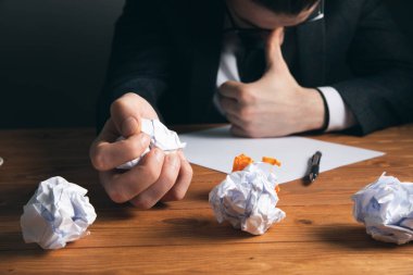 Bir adam masasında kağıt kırıntıları bırakıyor.