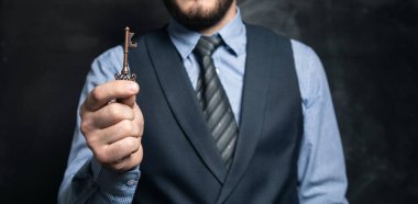 İş adamı siyah arka planda anahtarları elinde tutuyor.