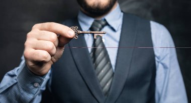 İş adamı siyah arka planda anahtarları elinde tutuyor.