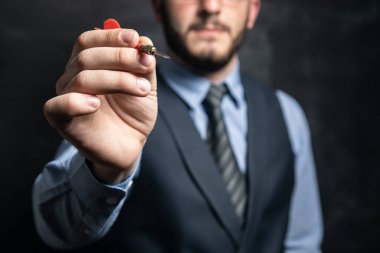 Elinde kara arka planda dart tutan bir işadamı