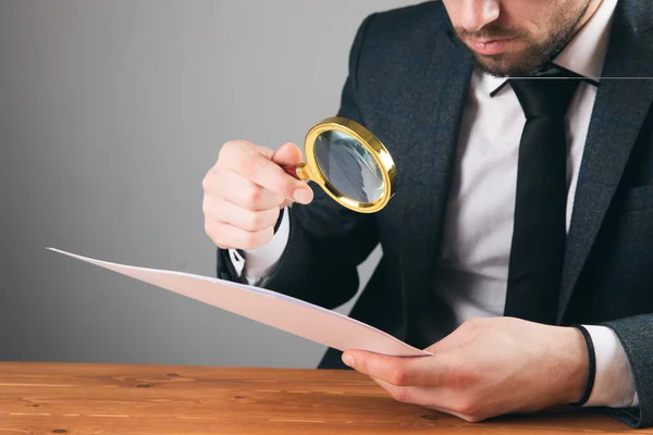 Ein Mann Anzug Mit Lupe Betrachtet Ein Papier Auf Grauem — Stockfoto