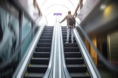 Metronun çelik yürüyen merdiveninde yürüyen bir adam.