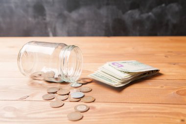 Bozuk paralar ve banknotlar ahşap bir masada cam bir şişeden dökülür.