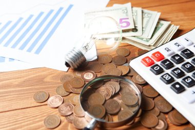 concept of studying costs. coins next to calculator, magnifier and lamp on the table
