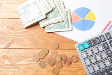 calculator, money and statistics on a wooden table