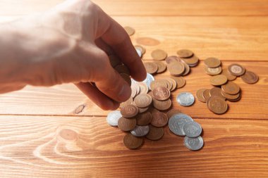 man counting coins on wooden table
