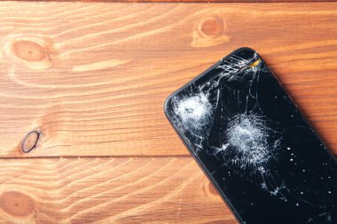 Ahşap arkaplanda kırılmış akıllı telefon ekranı
