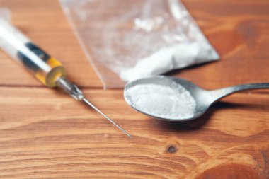 syringe and powder in a package spoon on a wooden background
