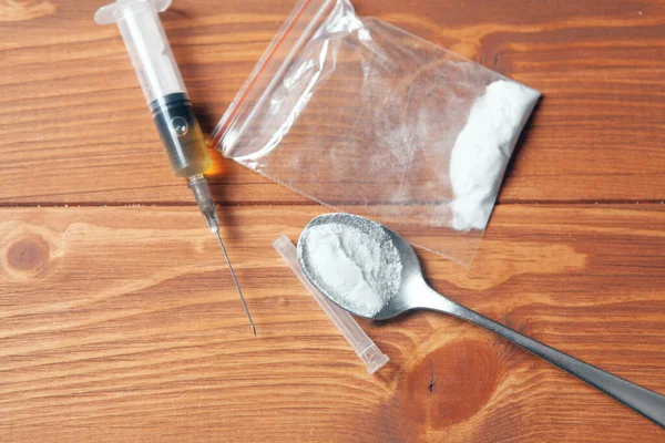 syringe and powder in a package spoon on a wooden background