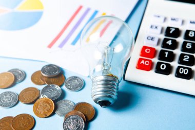 business idea concept. coins next to a calculator and a lamp on the table on a blue background