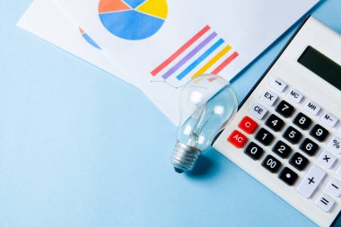 business idea concept. coins next to a calculator and a lamp on the table on a blue background
