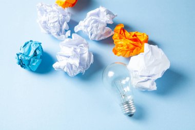 magnifier looks at a lamp and a wad of papers on a blue background