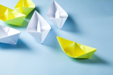 white and yellow paper boats on a blue background