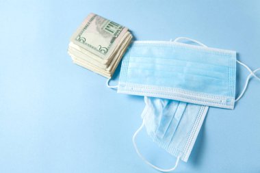 mask and dollar bills on a blue table