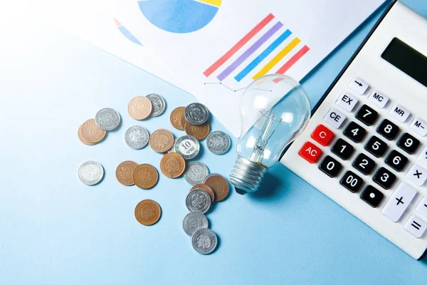 business idea concept. coins next to a calculator and a lamp on the table on a blue background