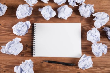 wads of papers on a wooden desktop and a notebook