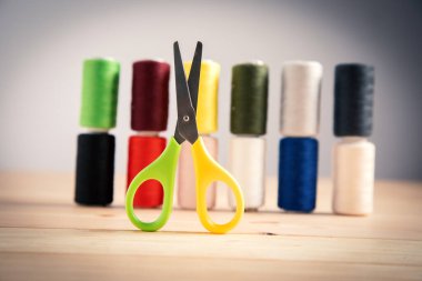 multicolored threads and scissors on a gray background