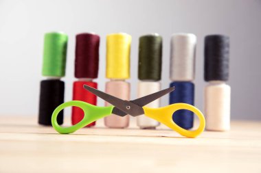 multicolored threads and scissors on a gray background