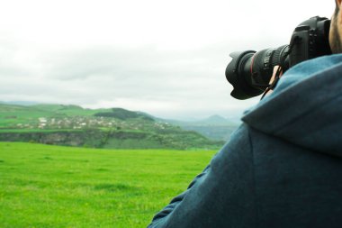 Bir adam gün boyunca yeşil bir alanda fotoğraf çekiyor.