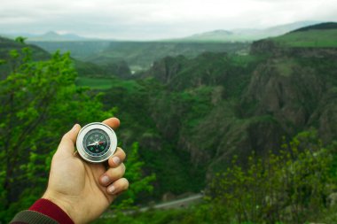 Gün boyunca bir uçurumun arka planında bir pusula tutmak