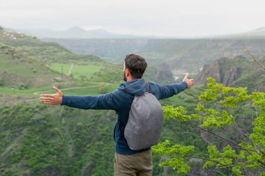 Bir adam gün boyunca elleri açık bir şekilde uçurumun kenarında durur.