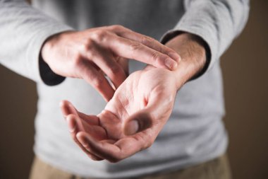 Bir adam nabzını bileğinde kontrol eder.