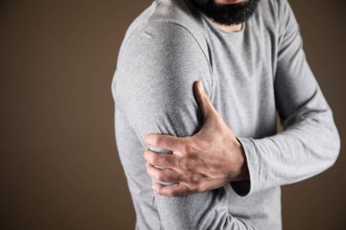 Genç bir adamın kolu acıyor.