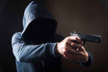 Karanlık bir arka planda silah tutan bir adam.