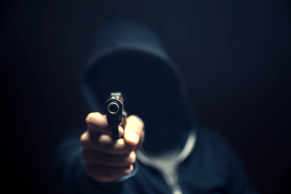 мужчина, держащий пистолет на темном фоне