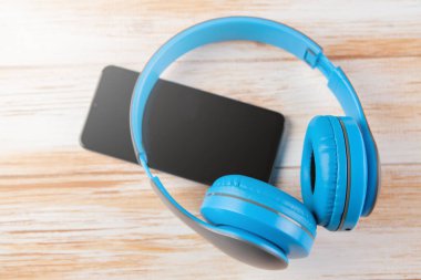 büyük kulaklıklar ve mavi arka planda bir telefon.
