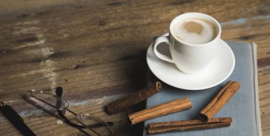 kahve, tarçın ve ahşap masada bir kitap.